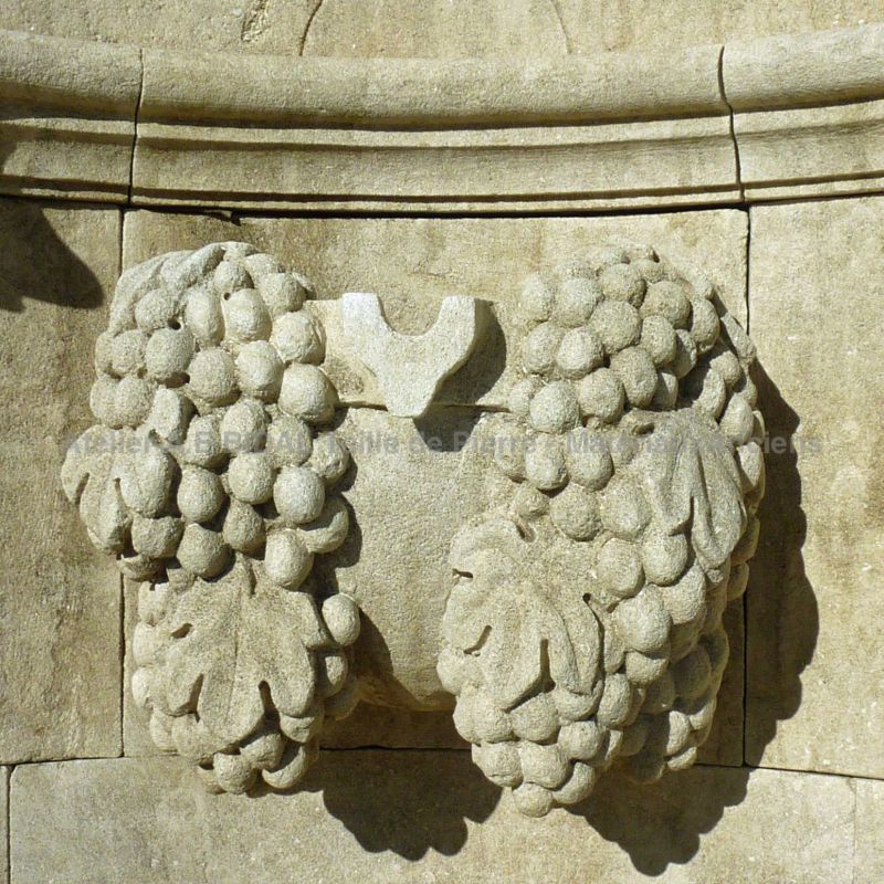 Sculpture en pierre représentant des grappes de raisin - fontaine décorative d'extérieur.