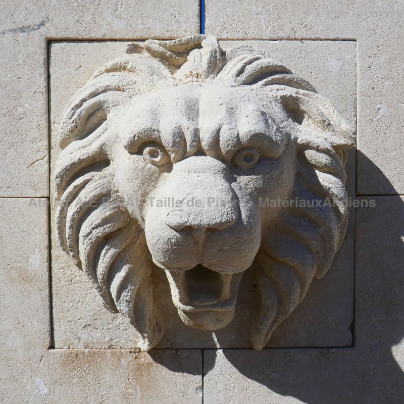 Sculpture en pierre sur fontaine murale de style rustique : tête de lion