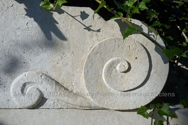 Détail de la volute sculptée à la main sur le fronton de notre fontaine murale en pierre de taille.